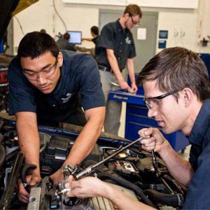 two young men working on a car engine